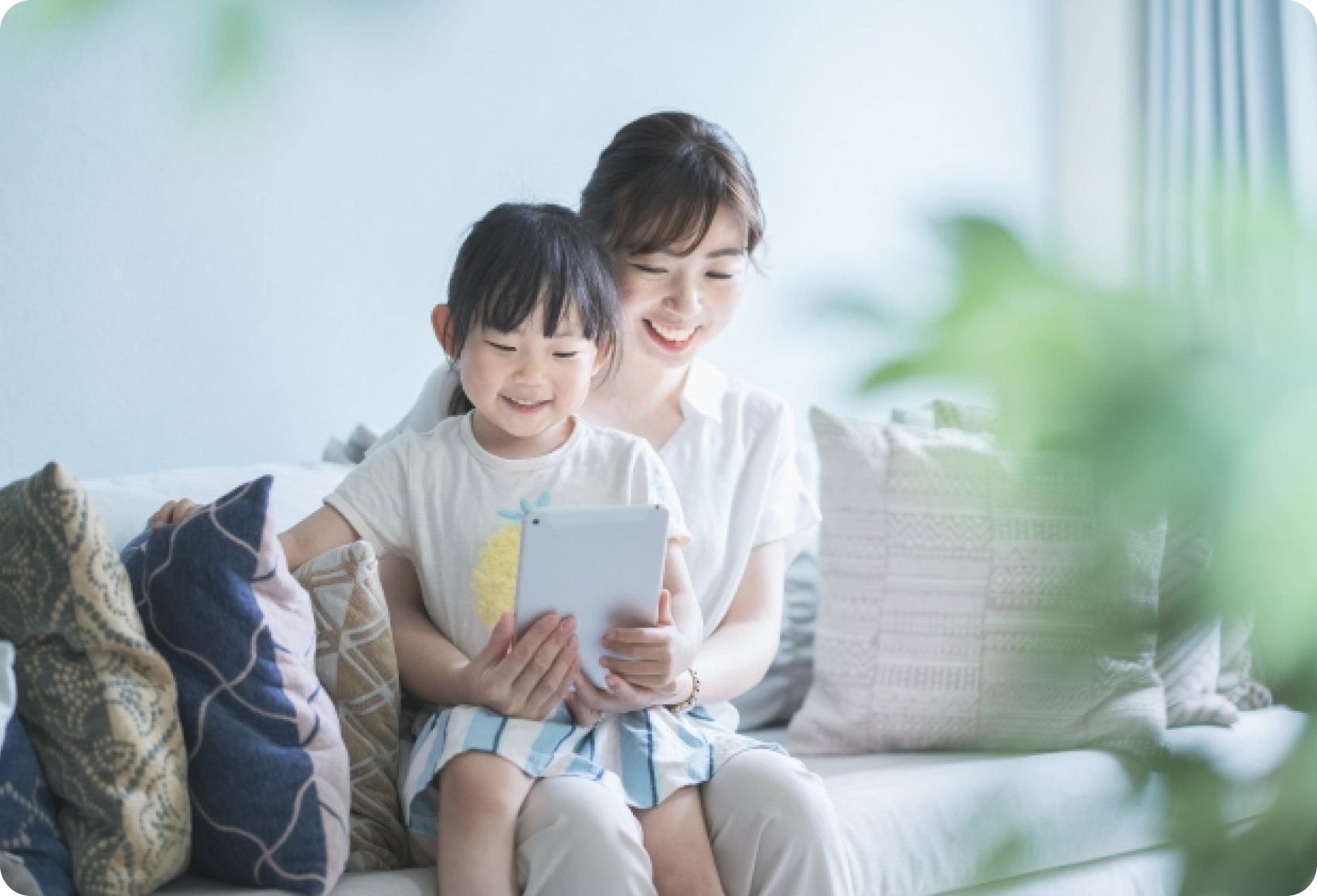 ソファでタブレットを見る親子